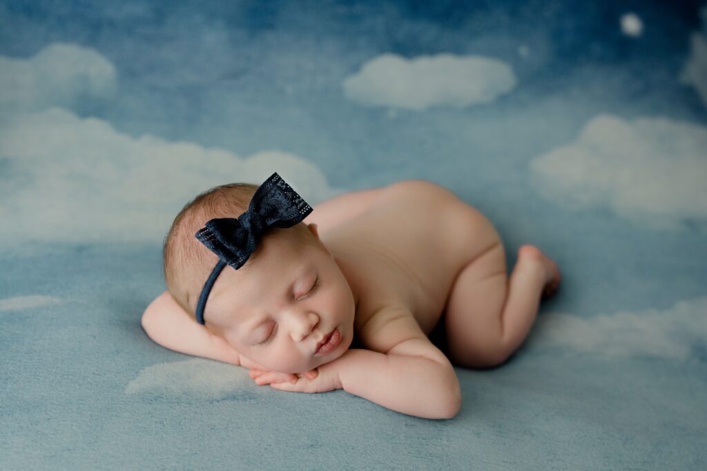 newborn baby girl birmingham al on cloud backdrop with blue bow 
